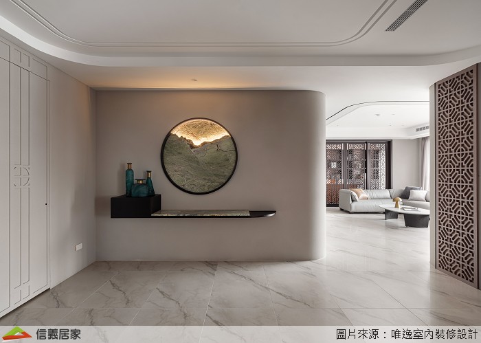 玄關牆面設計一面圓形窗景，透過光影的映照，在空間中重新架構組織輪廓，另一側設置隱藏收納櫃，讓居家收納隱形顯得美觀不繁雜。玄關主牆轉角處的圓弧形水墨風華，便是概念意化後落實的呼應，並展延至中島區域。