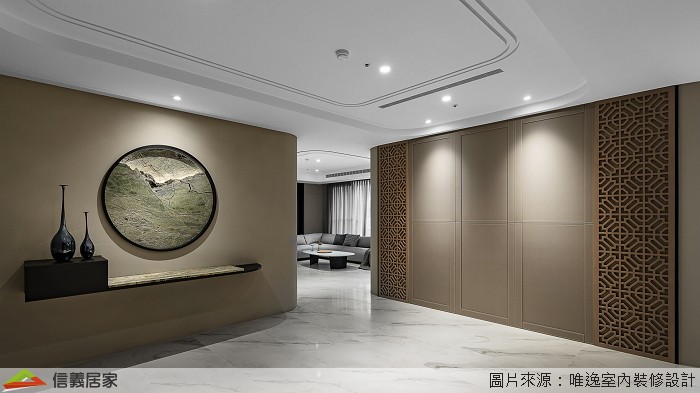 玄關牆面設計一面圓形窗景，透過光影的映照，在空間中重新架構組織輪廓，另一側設置隱藏收納櫃，讓居家收納隱形顯得美觀不繁雜。玄關主牆轉角處的圓弧形水墨風華，便是概念意化後落實的呼應，並展延至中島區域。